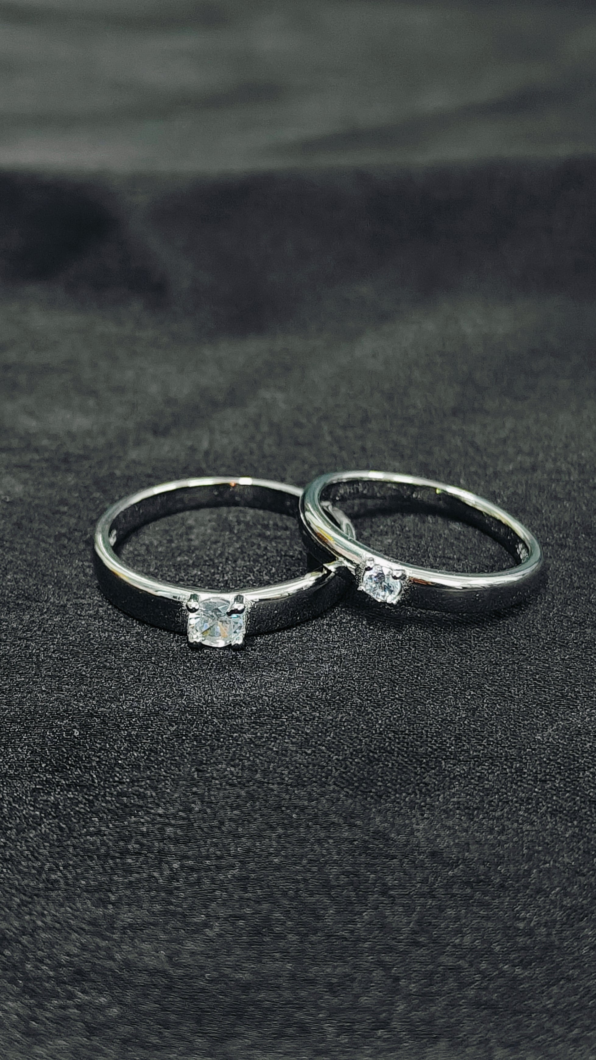Two silver rings with gemstones on a black fabric background
